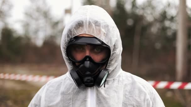 Man in bio-hazard suit and gas mask walks and looks straight into the camera — Stock Video