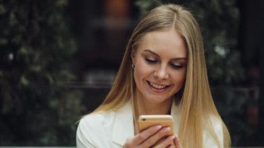 Sevimli sarışın kadın bir şey kafede masada oturan onun smartphone içinde okur