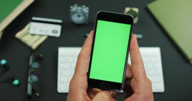 Adam yeşil ekran ile smartphone bir çalışma tablo üzerinde tutar.