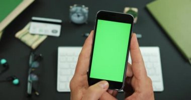 Adam ile yeşil perde smartphone bir çalışma tablo üzerinde tutan ve üzerine bir şeyler musluklar