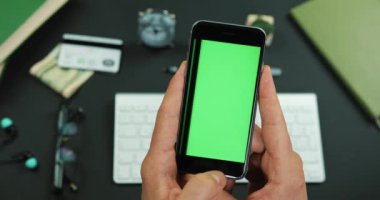 Adam yeşil ekran ile smartphone bir çalışma tablo üzerinde tutan ve üzerine bir şey verilirse