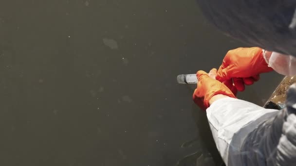 Man in handschoenen neemt vuil water voor een test — Stockvideo