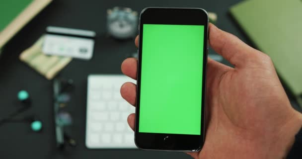 男は作業テーブルの上の緑色の画面を持つスマート フォンを保持します。 — ストック動画