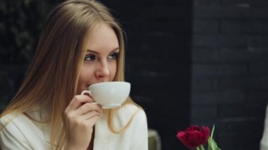 Çok güzel genç kadın kafede oturmuş kahvesini içer