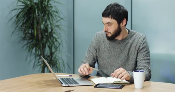 Homem toma notas de seu laptop para seu laptop — Vídeo de Stock
