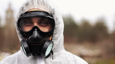 Biyo-tehlike takım elbise ve Gaz Maskeli adam doğruca kameraya benziyor