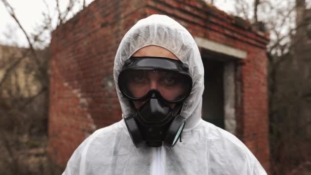 Homme en costume bio-danger et masque à gaz regarde droit dans la caméra — Video