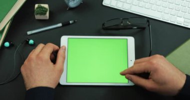 Tablet yeşil ekran ile çalışma tablosu üzerinde yatıyor ve adam üzerine bir şey verilirse