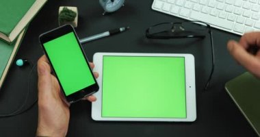Adam onun gözlük yeşil ekran tabletiyle tarafından masanın üzerine koyar ve smartphone onun kolundan tutar