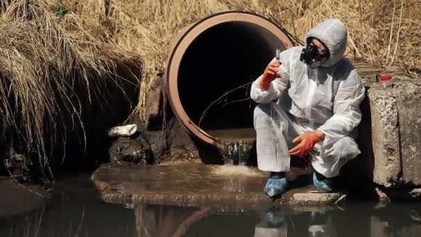 Hombre en traje de bio-peligro y máscara de gas comprueba la contaminación del agua exterior — Vídeos de Stock