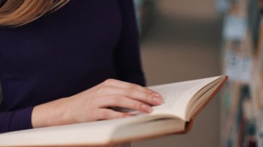Kız kütüphanede kitap okuma sayfaları üzerinde parmaklarını tutar