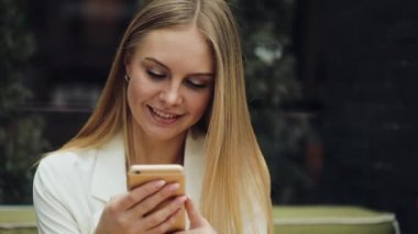 Sevimli sarışın kadın bir şey kafede masada oturan onun smartphone içinde okur