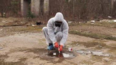 Su ve toprak analizi için biyo-tehlike takım elbise ve Gaz Maskeli adam alır