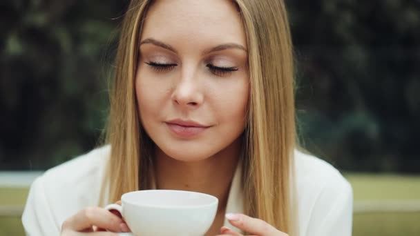 Adorável jovem bebe seu café sentado no café — Vídeo de Stock