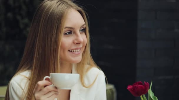 Adorável jovem bebe seu café sentado no café — Vídeo de Stock