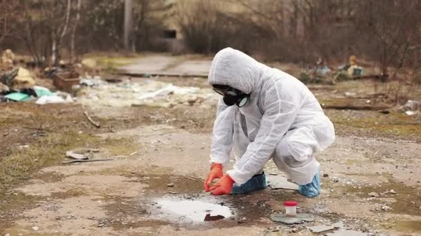 Человек в защитном костюме и противогазах забирает воду и землю для анализа — стоковое видео