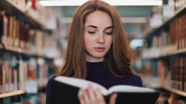 Düşünceli genç kız öğrenci Kitaplığı'nda bekleyen bir kitap okur