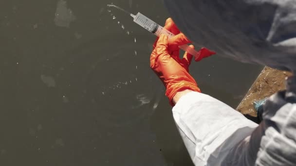 Hombre con guantes toma agua sucia para una prueba — Vídeos de Stock