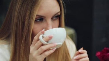 Çok güzel genç kadın kafede oturmuş kahvesini içer