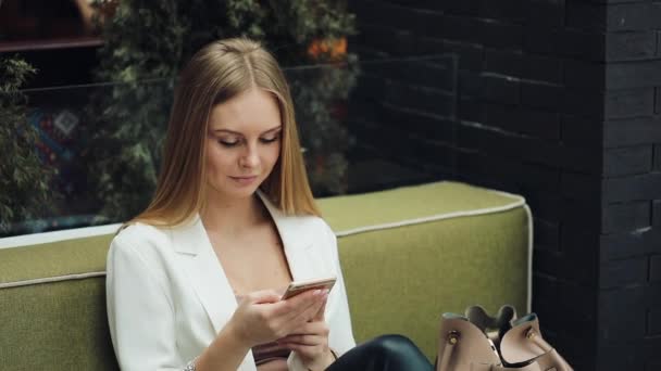 Meisje controleert haar telefoon zittend op de Bank — Stockvideo
