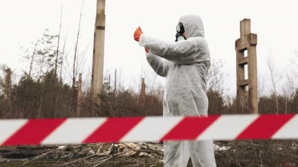 Man in bio-gevaar pak en gasmasker neemt foto's op zijn smartphone — Stockvideo