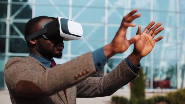 Hombre afroamericano juega con auriculares VR de pie afuera — Vídeos de Stock