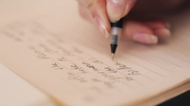 Kız bir şey kitaplığındaki masada oturan bir kitap yazıyor