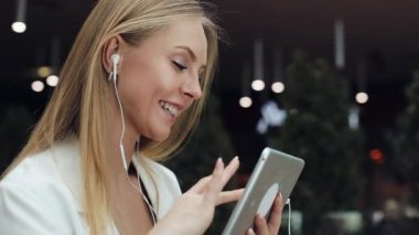 Çekici genç kadın gülümsüyor kulaklık bir tablet ile çalışma