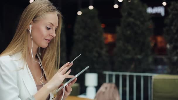 Mujer joven sonriente toma datos de la tarjeta de crédito de oro que trabaja con una tableta — Vídeo de stock