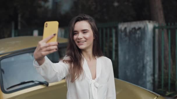 Young Brunette Smiling Beautiful Girl Ending Video Call via Her Smart Phone, Waving Bye-Bye Outdoor (англійською). Молода дівчина робить і надсилає відеоповідомлення, стоячи надворі. — стокове відео