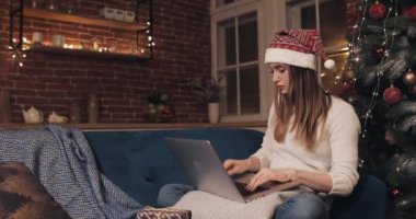 Noel ağacının yanında oturan çekici beyaz kız dizüstü bilgisayarının düşünce ve emirlerini kullanıyor. Hediye kutusu ellerine düştü. Tatmin olmuş ve kameraya mutlu görünüyor.