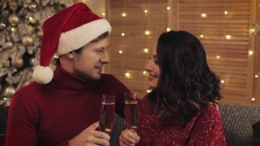Genç bir çift Noel ağacının yanındaki koltukta oturuyor. Arka planda, Champagne bardaklarını tokuşturuyor. Güzel bir aile kameraya bakıyor. Tatil ve Yeni Yıl Kapanışı kavramı.