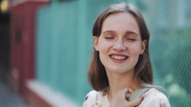 Kahverengi saçlı, mavi gözlü ve çilli, turkuaz telli gülümseyen kafanın yanında duran güzel, çekici bir genç kadının portresi. Kameraya Bakan ve Gülümseyen Kız.