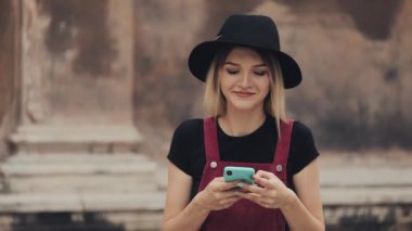 Genç Preety Gülümseyen Sarışın Kız Burnuna piercing takmış Akıllı telefonunu kullanıyor Yazıyor ve gülüyor Şehir Caddesinde .