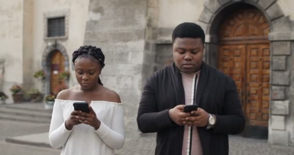 Casal jovem com celulares andando fora . — Vídeo de Stock