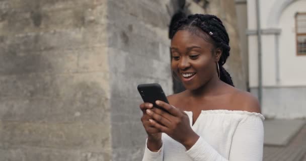 Junge Frau benutzt Smartphone, sieht schockiert und glücklich aus. — Stockvideo