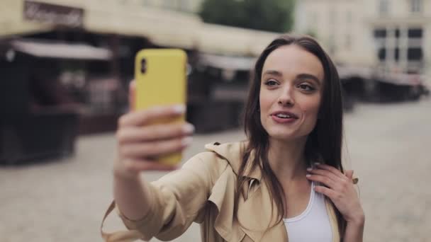 Schöne glückliche junge Mädchen, die ein Videoanruf hält Telefon vertikal lächelnd sprechen stehend auf der Straße Hintergrundkommunikation Konzept der Stadt. — Stockvideo