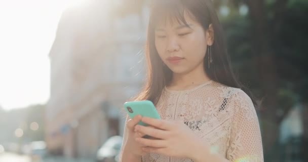 Asiatische Mädchen mit Telefon in Sonnenstrahlen. — Stockvideo