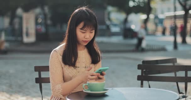 Дівчина п'є каву і використовує смартфон — стокове відео