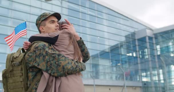 Mladý voják objímal svou přítelkyni a hladil ji po vlasech. Muž ve vojenské uniformě objímající ženu, který vypadá šťastně, když stojí venku. Rodinné shledání. Koncept vojenské služby. — Stock video