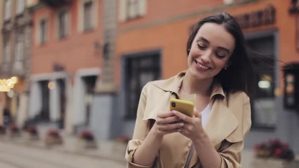 Jovem mulher sorridente atraente usando seu Smartphone em pé na Old City Street. Conceito de comunicação . — Vídeo de Stock