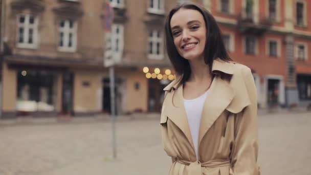 Achterzijde volgen Beelden van mooi jong meisje lopen in de straat draaien rond op zoek en glimlachen voor de camera. — Stockvideo