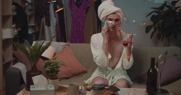 Front view of angry transgender having reletionship crisis, holding cigarette and drinking wine. Nerveux trans homme assis sur le canapé, querelle avec amant tout en parlant sur smartphone . — Video