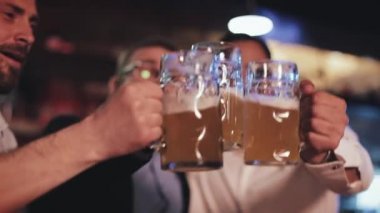 Üç mutlu arkadaş barda iyi vakit geçirirken cam bira bardaklarını tokuşturuyor. 30 'lu yaşlarda, işten sonra bira içip sohbet eden bir adam. Boş zaman ve dinlenme kavramı.