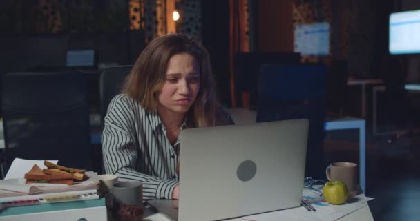 Trött kvinna kontorschef arbetar övertid på laptop och ser upprörd. Stressad flicka hittar misstag i sin rapport när hon sitter vid skrivbordet i tomma nattkontor. Begreppet överarbete. — Stockvideo
