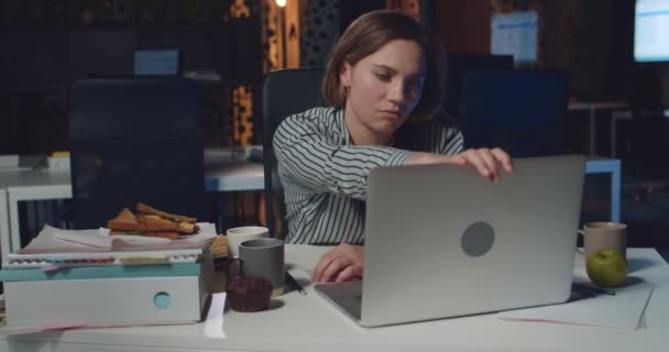 Femme surmenée gestionnaire de bureau fermeture ordinateur portable et mettre la tête sur les mains tout en étant assis au bureau. Jeune femme d'affaires à la recherche fatiguée tout en travaillant avec l'ordinateur tard dans la nuit . — Video