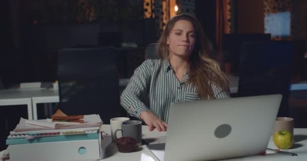 젊은 사업가가 의자를 빙빙 돌면서 노트북으로 타자를 치기 시작하였다. 여성 사무직 근로자가 밤에 빈 사무실에서 일하는 동안 컴퓨터를 사용하고 있습니다. 일하는 것이라는 개념. — 비디오