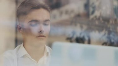 Bilgisayarla masada oturan genç iş adamlarına yakın çekim. Beyaz gömlekli çekici erkek menajer ciddi bir işte çalışıyor.