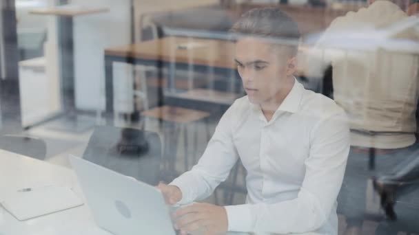 Jovens negócios felizes sentados em uma mesa em um café trabalhando em um laptop. Vencedor olhando para laptop mostrando sim gesto, celebrando o sucesso, boas notícias na web, desfrutando triunfo, fez isso — Vídeo de Stock