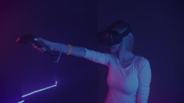 Sanal Gerçeklik Kulaklık Giyen, Joystick Kontrolörleri Tutan, Çeken, Soyut Neon Işıklandırma Arkaplanda Oyun oynayan Genç Kız. VR, Eğlence Konsepti.
